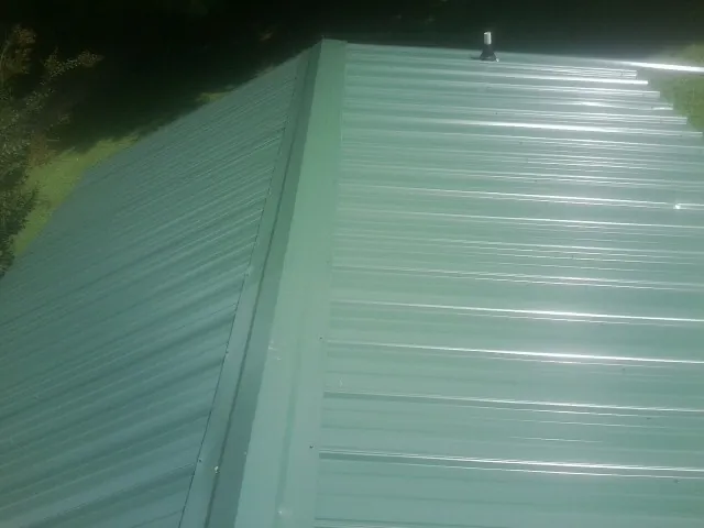 New green metal panels meeting at the ridge of a roof — Flat Roof Repair work by our crew in Chehalis