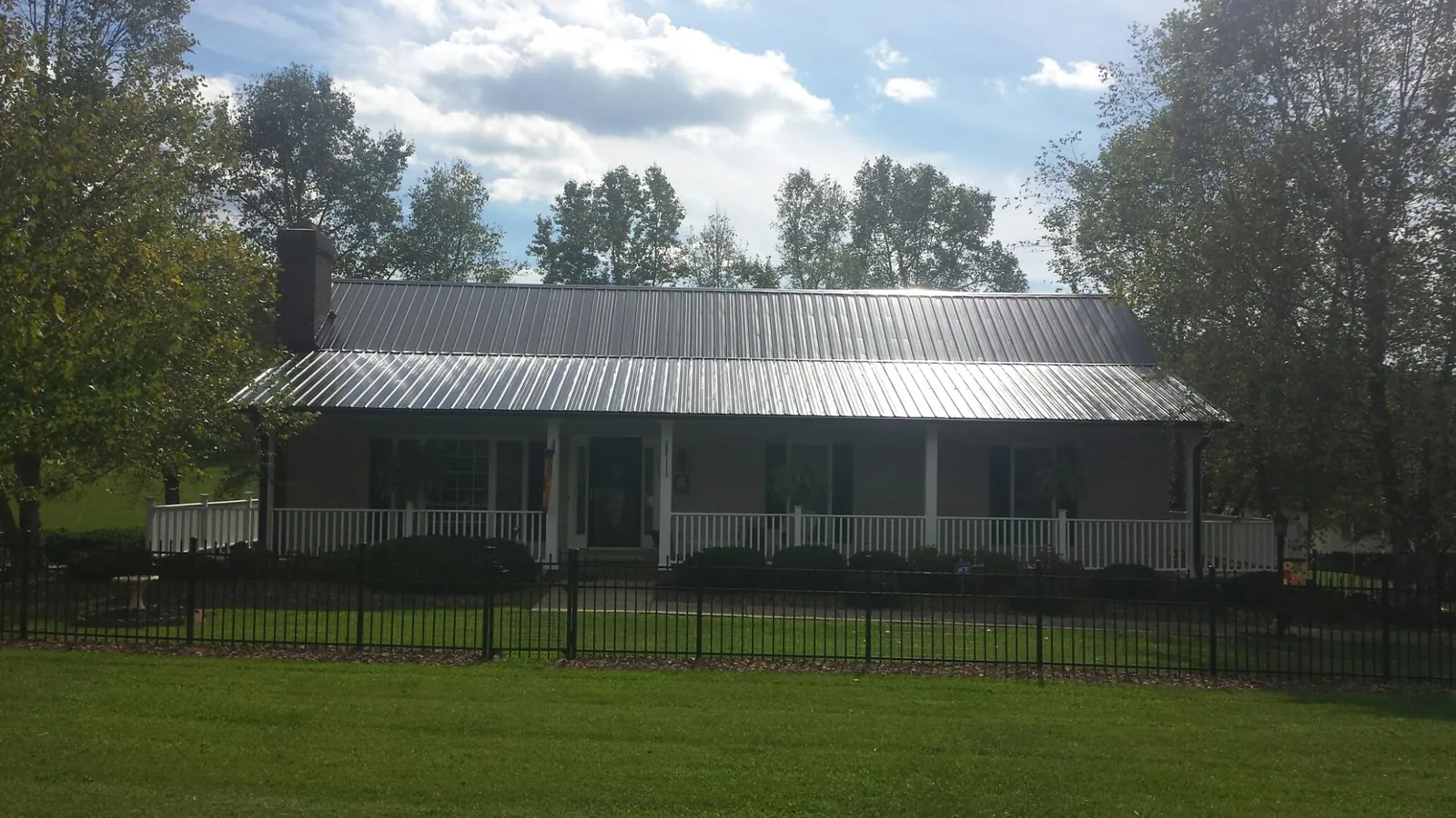 Gray metal roof on a brick ranch with a full width front porch — Gutter Guard Installation work by our crew in Chehalis