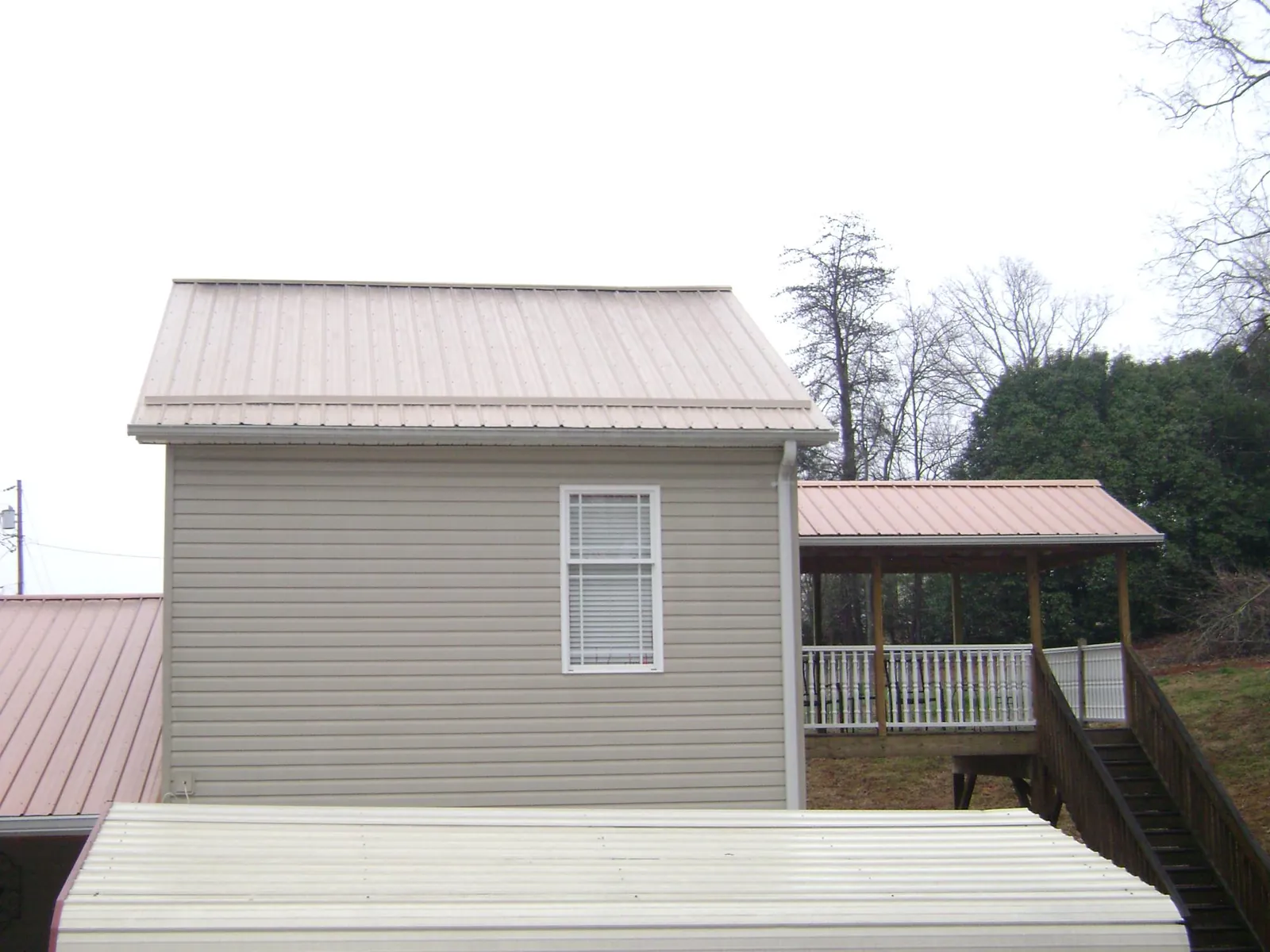 Tan metal roofs on a two story addition and attached porch, from a Roof Replacement job in Chehalis