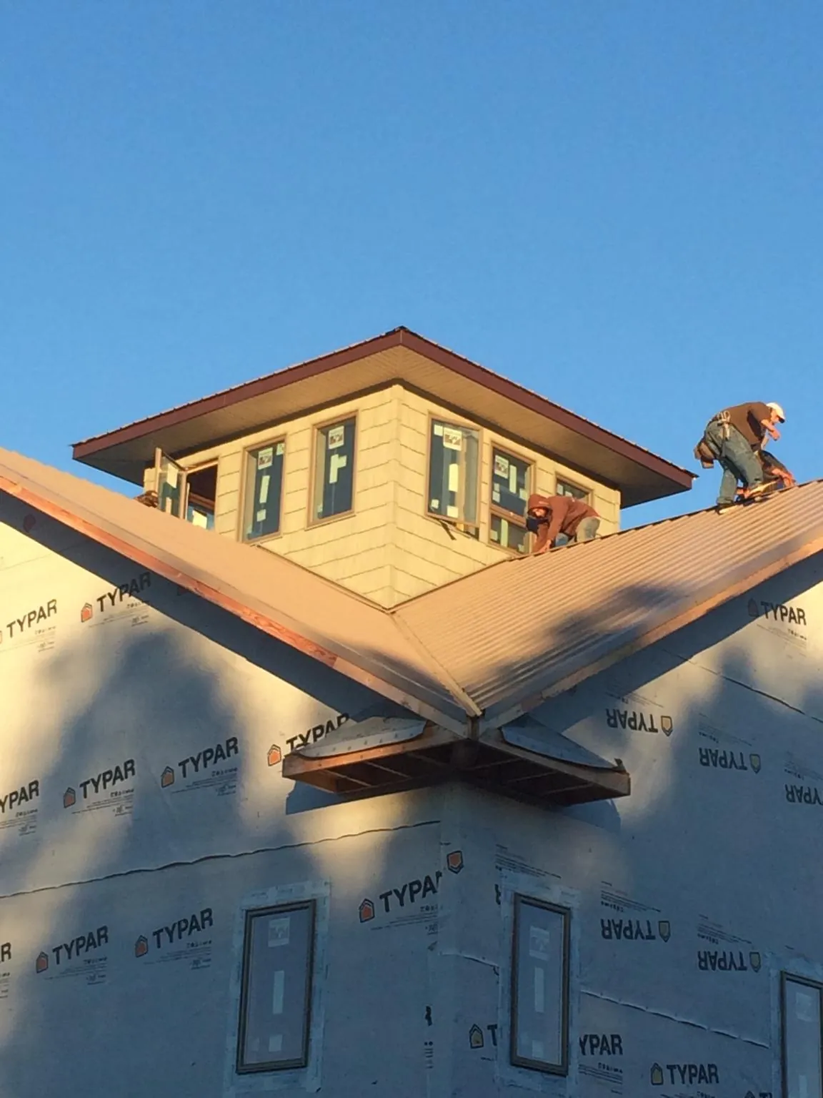 Roofers working around a rooftop cupola on a new metal roof at sunset — Roof Waterproofing in Chehalis by Roofing Brothers